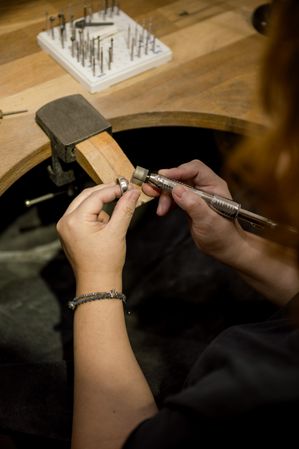 unrecognizable woman grinding ring in jewelry atelier