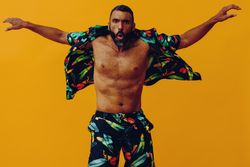 Male with opened brightly patterned shirt and open arms, copy space