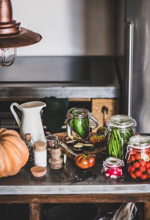 Rustic kitchen with pickled vegetables, spices and herbs on counter, vertical composition