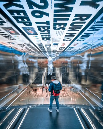 Man with backpack standing on staircase decorated with mirrors