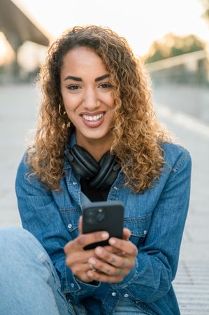 Smiling woman with smartphone on street
