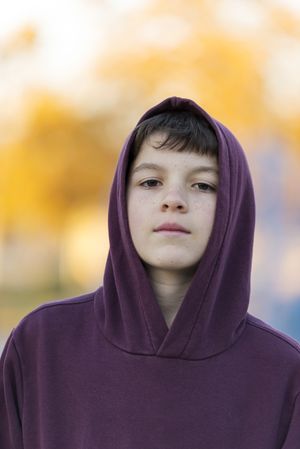 Outdoor portrait of teen boy in hoodie at park