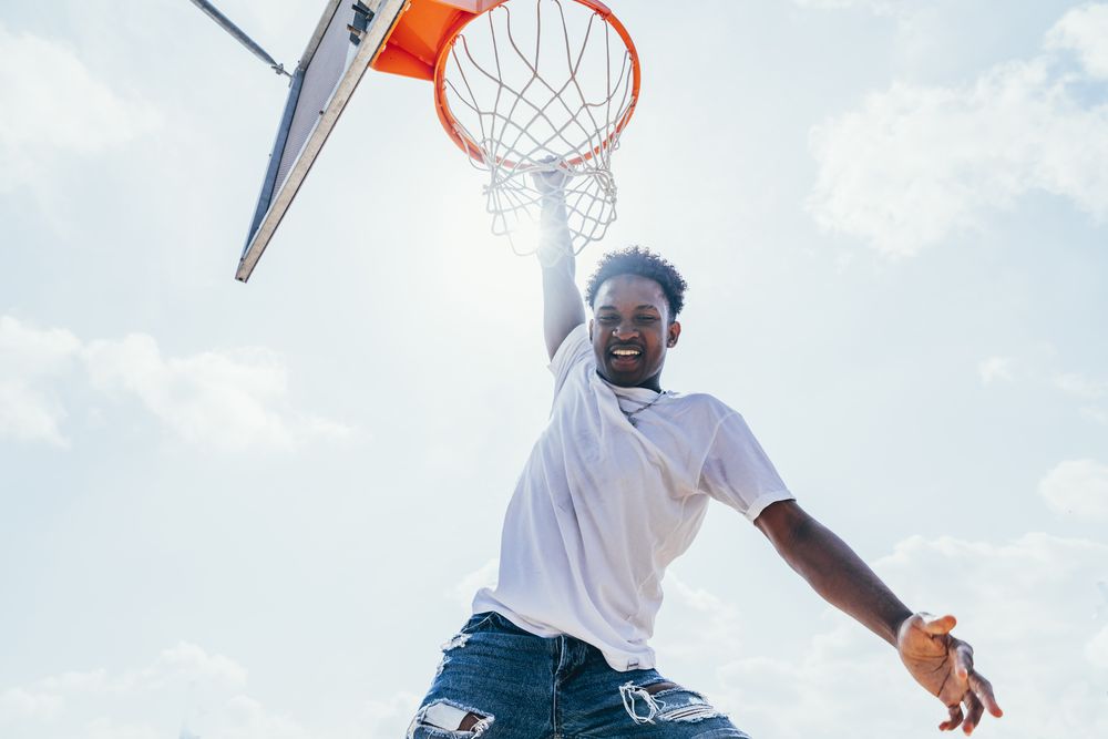 Black sportsman hanging on basketball lap