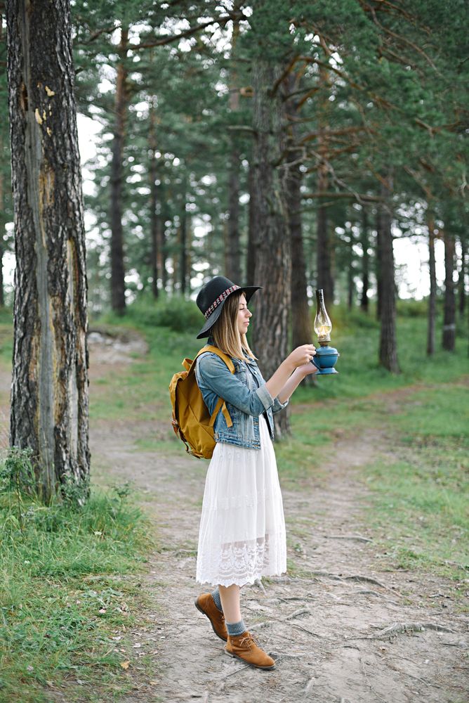 Woman with hat and holding burning gas lamp in the woods