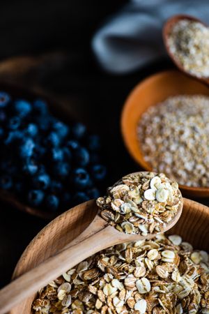 Wooden spoon with dry oats and blueberries on kitchen counter