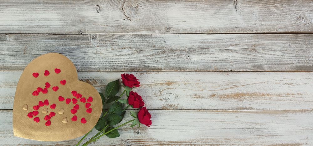 Valentine’s Day with heart of gold and rose flowers on aged wood
