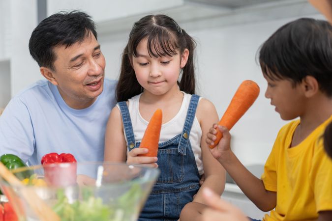 Happy Asian family with carrots in the kitchen together