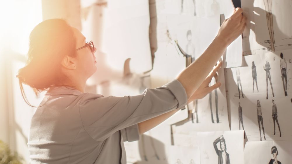Female fashion, designer,  Choosing Sketches for Her Project and Pinning them to the Wall.