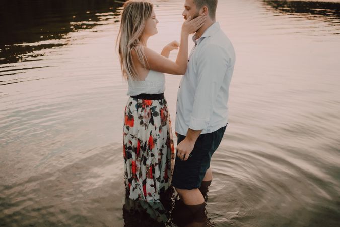 Loving couple standing ankle deep in water on beach