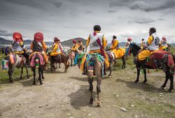 Tibet - August, 29 2014: Anonymous men riding horses on cloudy day