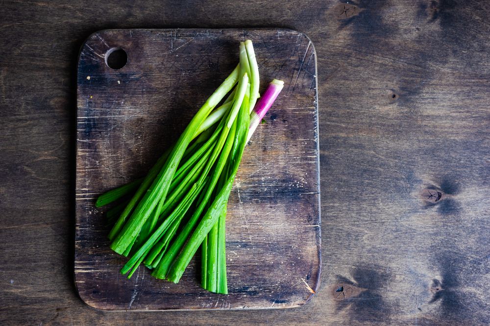 Fresh green onions on wooden board