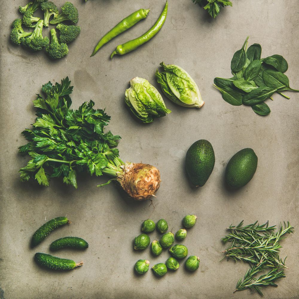 Arrangement of fresh green garden vegetables on concrete surface, square crop