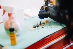 Tattoo artist loading up gun with ink