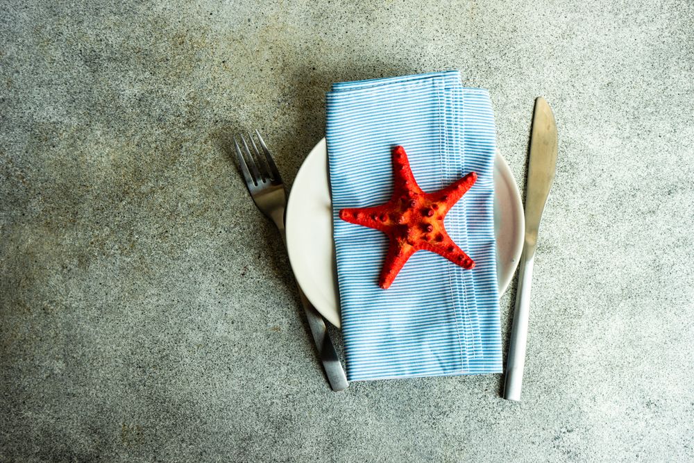 Red sea shell on table setting with blue napkin