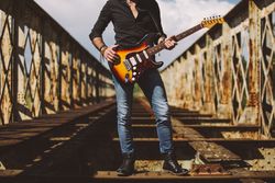 anonymous Man with guitar standing on bridge