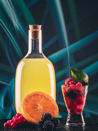 Bottle with drink near shot and fruits