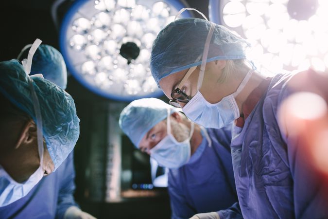 Concentrated female surgeon performing surgery with her team in hospital operating room