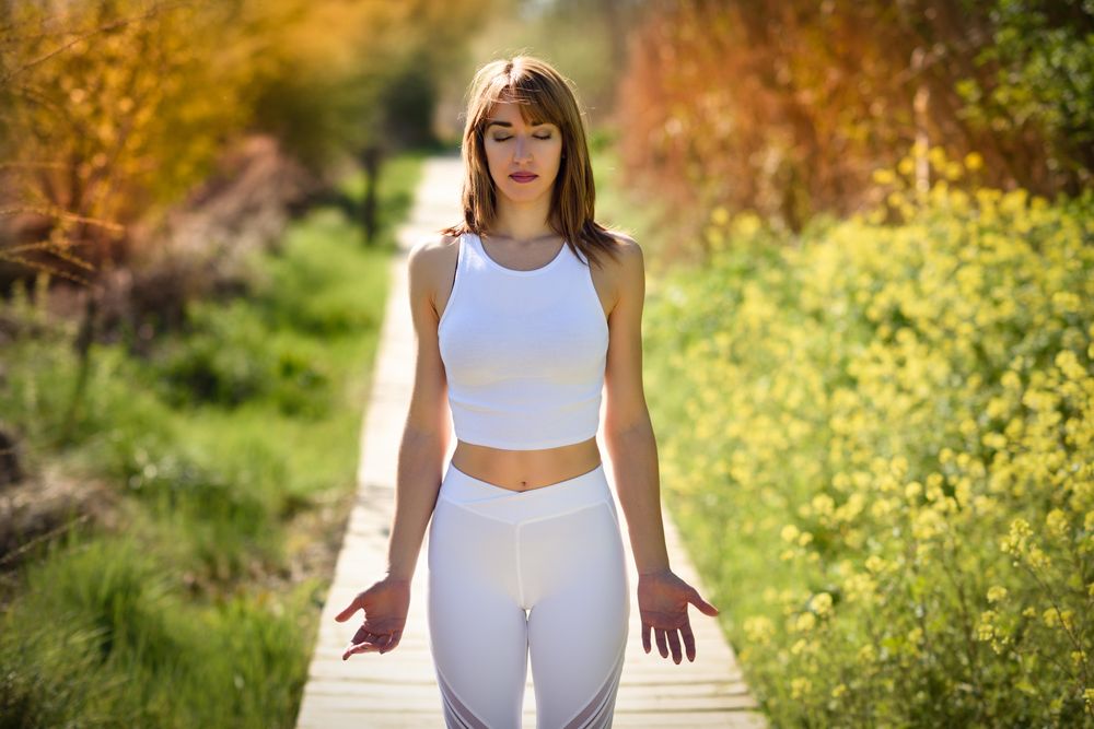 Female wearing light sport clothes standing on walkway in forest