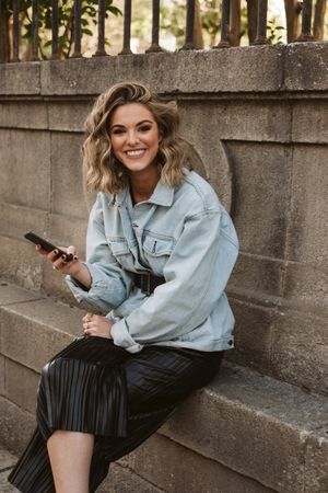 Woman using smartphone near park fence