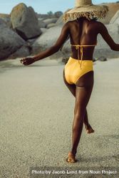 Rear view of woman wearing bikini and straw hat on the beach 0VNOY0