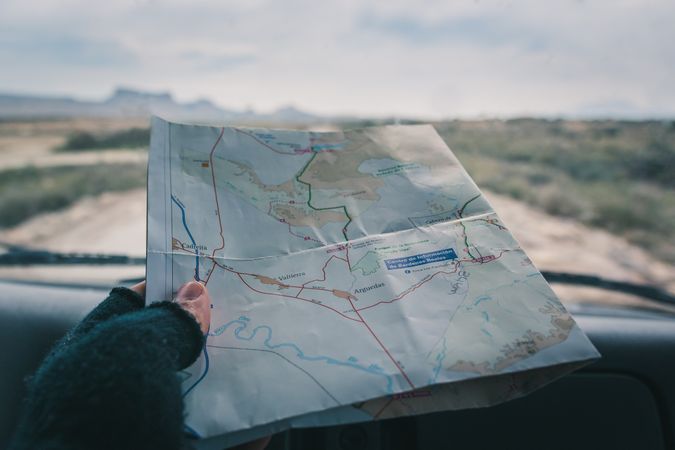 Man in car studying road map driving on road