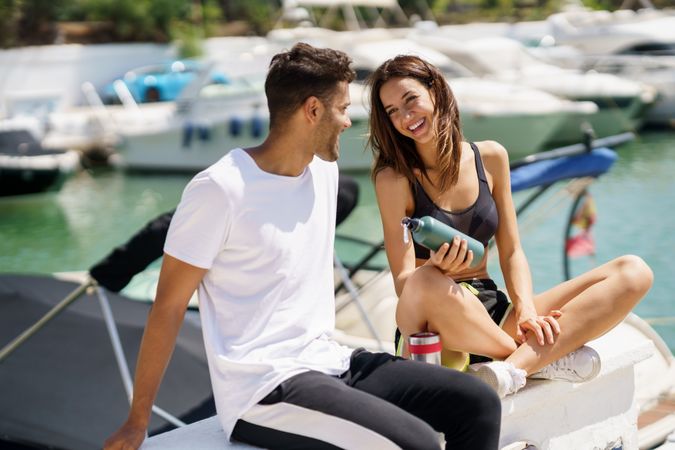 Male and female talking together on pier with water bottles