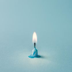 Lit blue candle on blue background