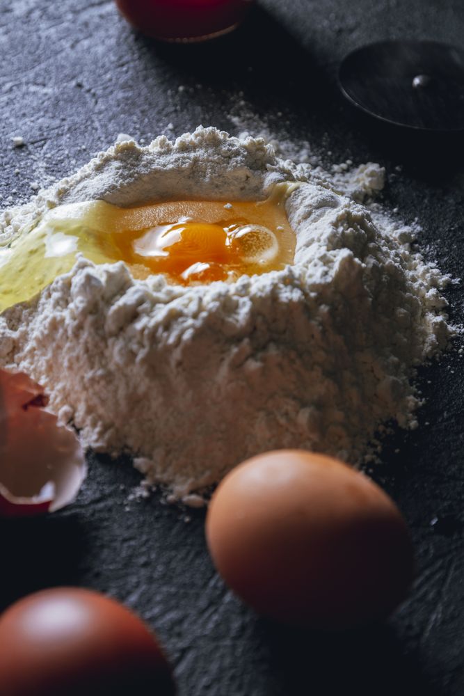 Broken egg and flour on dark background
