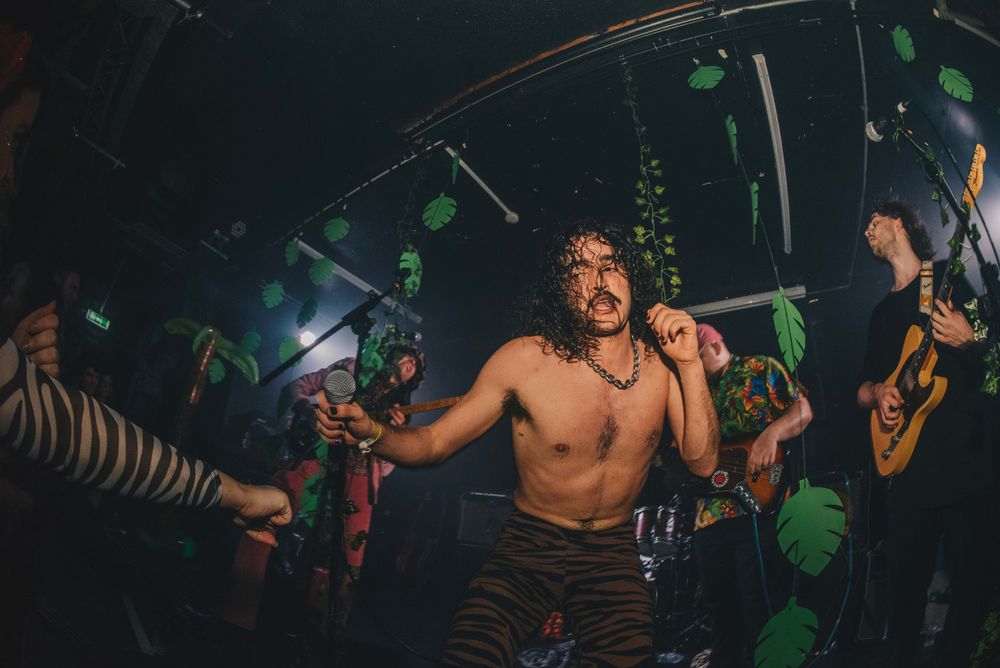 Sweaty long-haired shirtless male musician grabs microphone on stage during concert
