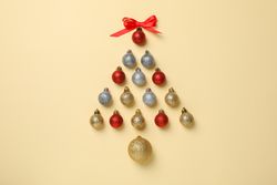 Christmas tree made of baubles on beige background, space for text