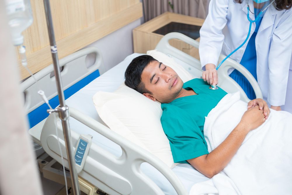 Physician treating sick man in hospital bed