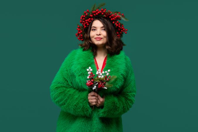 Smiling woman in green coat and red berry wreath