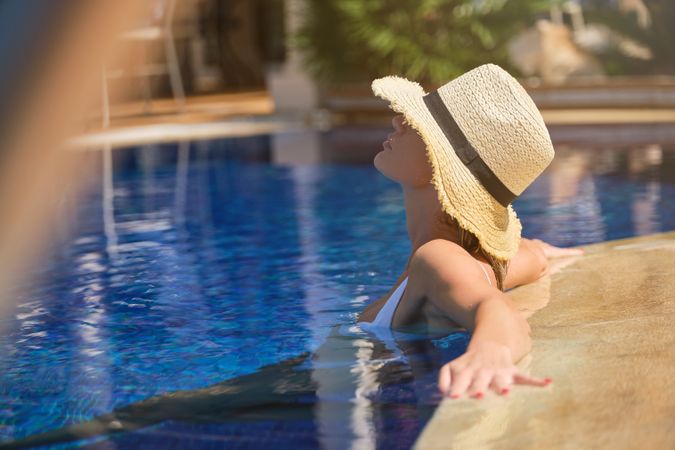 Anonymous female tourist resting in pool at resort