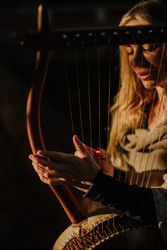 Sensual female musician playing lyre in garden
