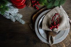 Top view of holly berries on xmas table setting with copy space