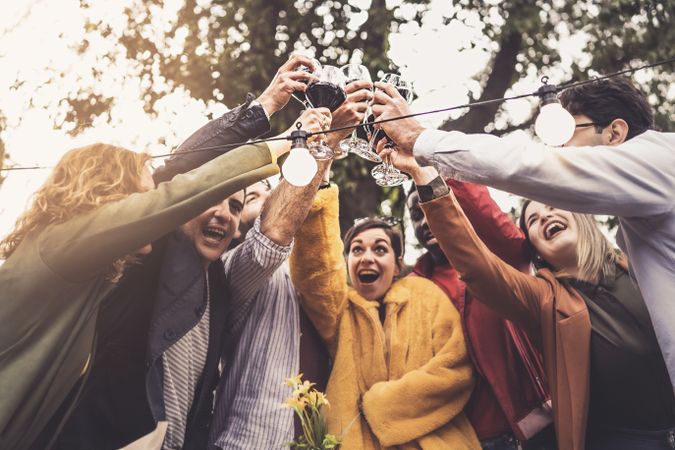 A group of friends of different ethnic backgrounds meet at sunset in the countryside to toast together on the terrace of the farmhouse restaurant
