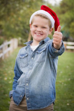 Young Boy Wearing Holiday Clothing Giving a Thumbs Up Outside