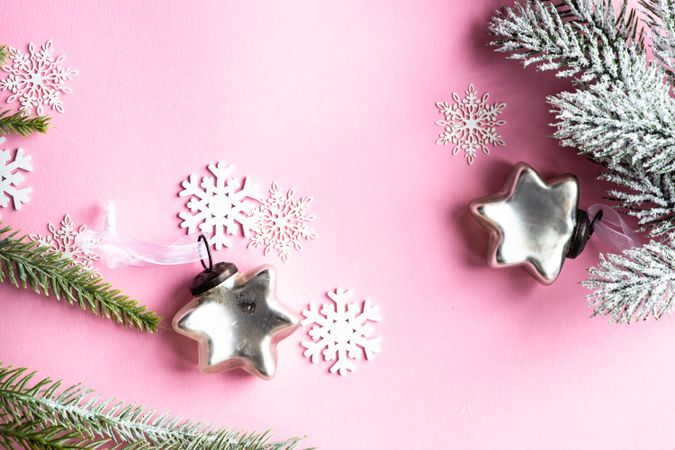 Silver star Christmas decorations and snowflakes on pink background