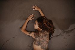 Tattoed woman lying on wet sand