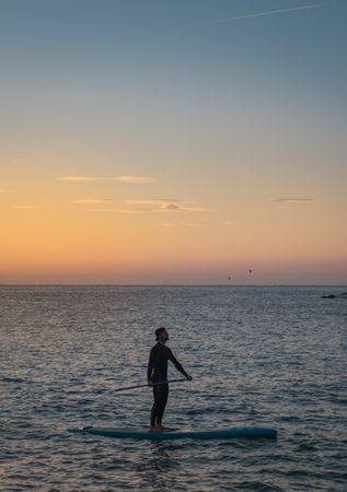 Man practicing paddle surfing with neoprene in a sunrise