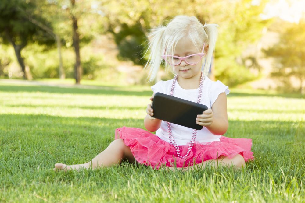 Little Girl In Grass Playing With Cell Phone