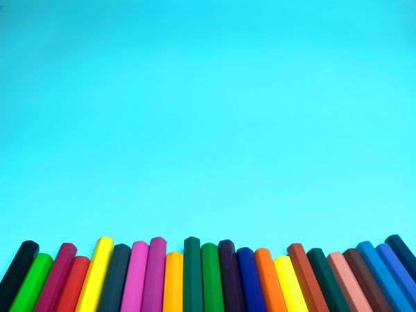 an arrangement of color pencils on a light blue background provides space for the text