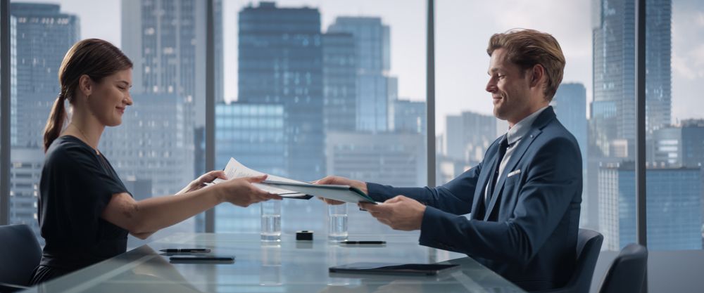 Female and Male Business Partners Sign Successful Deal, Shake Hands in Meeting Room in Skyscraper Office.