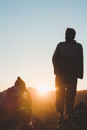 Man and woman enjoying sunset in autumn mountains