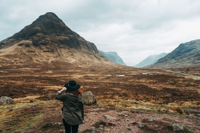 Redhead woman in hat against mountains