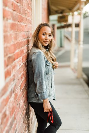 Side view of woman in denim jacket leaning on a wall