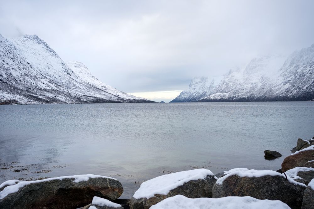 Scenic view from sea stones on snowy mountains