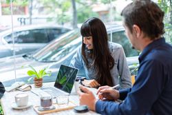 Man and woman have meeting at the coffee shop with cars outside front window