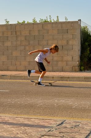 Active boy riding skateboard along roadway