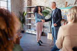Two businesspeople shaking hands in agreement in the meeting room